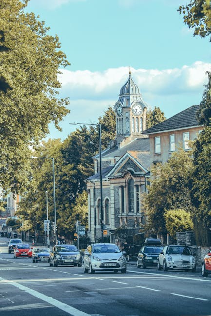 A busy residential street scene in Willesden with parked cars lining both sides of the road and moving vehicles, including a red Metroline bus on route 143 with destination 'Brent Cross' visible on th